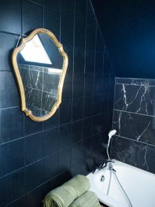 ein Badezimmer mit einem Spiegel, einem Waschbecken und einer Badewanne in der Unterkunft Gite traditionnel chez Léon Éguisheim in Eguisheim