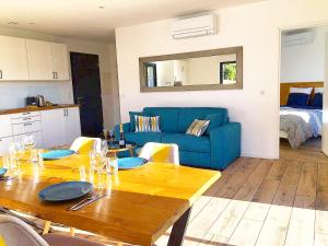 een woonkamer met een tafel en een blauwe bank bij Appartement & Jacuzzi dans l’Esterel proche Mer in Les Adrets de l'Esterel