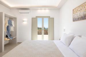 a white bedroom with a large bed and a window at Windmillside Luxury Villas in Emporio