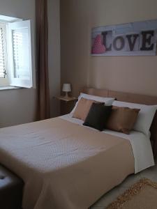 een slaapkamer met een groot bed met een liefdesbord aan de muur bij Mosa House in Aci Castello