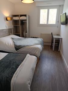 a room with three beds and a table and a window at Le Relais Du Velors in Beaumont-en-Véron