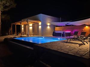 a swimming pool at night with chairs around it at Kavos beach house in Pefki Rhodes