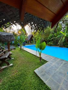 ein Resort mit einem blauen Pool mit einem Tisch und einer Bank in der Unterkunft Palmyra Nature Resort Sigiriya in Sigiriya