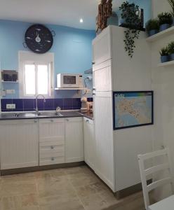 a kitchen with white cabinets and a clock on the wall at El Faro del Manteca in Cádiz