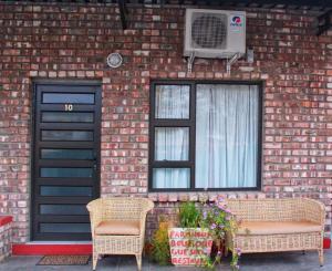 una casa de ladrillo con 2 sillas y una ventana en Farmhouse Boutique Guest 2, en Outjo