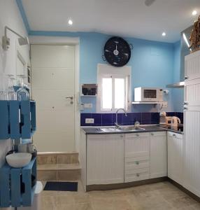 a kitchen with blue walls and a clock on the wall at El Faro del Manteca in Cádiz