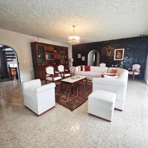 ein Wohnzimmer mit weißen Möbeln und einem Kronleuchter in der Unterkunft Casa Hamilton casa entera in Cuenca