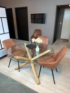 a glass table with two chairs and a vase of flowers at A Place To Stay Stavanger, apartment 4 in Stavanger