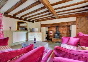 sala de estar con muebles de color rosa y chimenea en Half Moon Inn en Aylsham