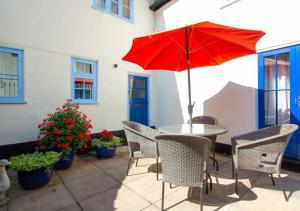 una mesa y sillas con una sombrilla roja en el patio en Half Moon Inn en Aylsham