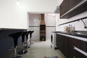 a kitchen with black bar stools and a counter at Casa Novo in Olímpia