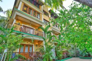 un edificio con balcones y árboles delante de él en Sovi - Luxury apartments with pool near Mandrem beach north Goa, en Mandrem