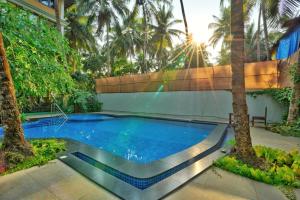 einen Pool in einem Resort mit Palmen in der Unterkunft Sovi - Luxury apartments with pool near Mandrem beach north Goa in Mandrem