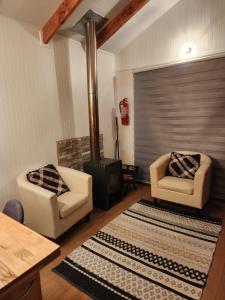 a living room with two chairs and a fireplace at Cabañas MAWEN in Chaitén