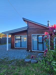 a house with windows and flowers in front of it at Cabañas MAWEN in Chaitén