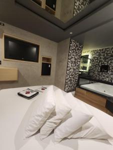 a bedroom with a white bed and a television at Motel Só Love 3 in Sao Paulo