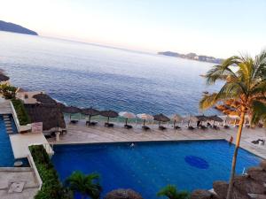 a view of a swimming pool with umbrellas and the ocean at Súper PENT-HOUSE ACAPULCO!! in Acapulco