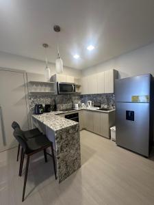 eine Küche mit einem Kühlschrank und einer Theke mit einem Stuhl in der Unterkunft Arcadia Condo Suites in Panama-Stadt
