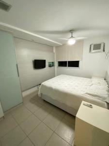 a white bedroom with a bed and a tv at Barra Family Resort, a sua melhor escolha in Rio de Janeiro