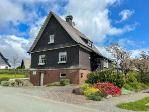 a house with a black roof and flowers in front at Zum Heidegarten in Winterberg