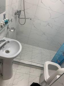 a white bathroom with a shower and a sink at Islomobod in Tashkent