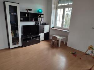 a living room with a television and a table and a chair at Im großen K in Ruppertshofen