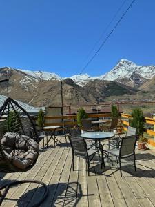une terrasse avec des tables et des chaises et des montagnes en arrière-plan dans l'établissement Guesthouse Elia, à Kazbegi