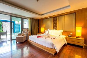 Un dormitorio con una cama grande y una mujer sentada en una silla en The Nchantra Beachfront Resort en Phuket