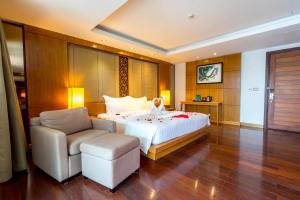 een slaapkamer met een bed, een bank en een stoel bij The Nchantra Beachfront Resort in Phuket
