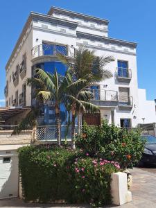 a building with a palm tree and flowers in front of it at APARTAMENTOS SAN NICOLAS in Adra