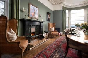 a living room with a fireplace and a table and chairs at Cairnbank House & Garden Apartment in Duns