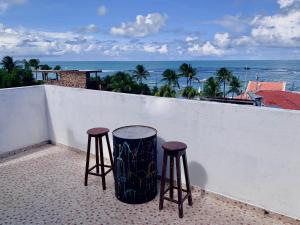 two stools on a balcony with a view of the ocean at Flats e Suítes Elcaline in Porto De Galinhas