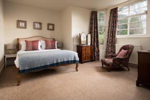 a bedroom with a bed and a chair and a window at Cairnbank House & Garden Apartment in Duns