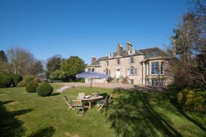 - une table avec un parasol dans la cour d'une maison dans l'établissement Cairnbank House & Garden Apartment, à Duns