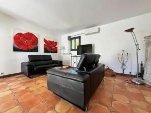 un salon avec un canapé en cuir noir et une télévision dans l'établissement Villa des Terriers - Villa privative 6 Personnes, à Antibes