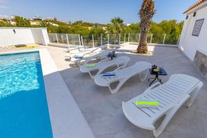 eine Reihe von weißen Liegestühlen neben einem Pool in der Unterkunft Fidalsa Grand Mediterranean Beachfront in Playa Flamenca