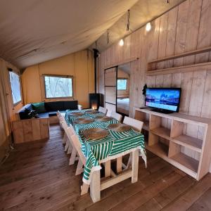 a room with a table and a tv in it at Heated & brand new Forestlodge in Renesse