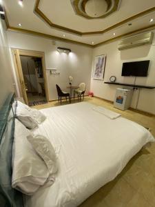 a large white bed in a room with a table at الينبوع الأخضر in Al Madinah