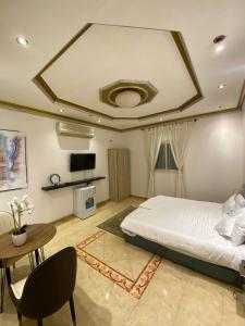 a bedroom with a bed and a table and a tv at الينبوع الأخضر in Al Madinah