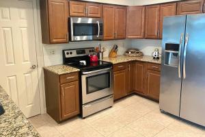 a kitchen with wooden cabinets and stainless steel appliances at Heated Saltwater Pool Home Minutes to Beach in Englewood