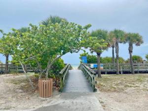 a wooden boardwalk leading to a beach with palm trees at Heated Saltwater Pool Home Minutes to Beach in Englewood