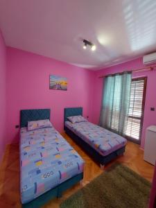 two beds in a room with pink walls at Barcelona Apartments in Tivat