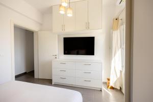 um quarto com uma cómoda branca e uma televisão de ecrã plano em FN Suites em Monolithos