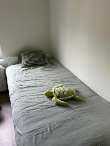 a stuffed turtle laying on a bed in a bedroom at Maison 2 chambres proche de Bruxelles in Mont-Saint-Guibert