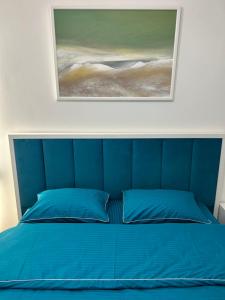 ein Schlafzimmer mit einem blauen Bett mit einem Gemälde darüber in der Unterkunft 2-к Люкс в центре in Tscherkassy