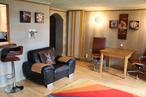 ein Wohnzimmer mit einem Ledersessel und einem Tisch in der Unterkunft The Retreat Tranquil Countryside Apartment in Larkhall