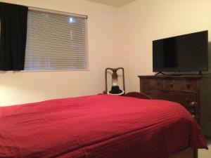 een slaapkamer met een rood bed en een flatscreen-tv bij Hobby Farm in the City in Spokane Valley