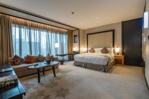 リヤドにあるAl Anoud Tower Residenceのベッドとソファ付きの広いホテルルームです。
