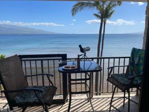 a table and chairs on a balcony with the ocean at Kanai A nalu in Wailuku