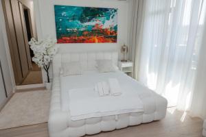 a white bed in a white bedroom with a painting at Studio Passion - Belgrade Waterfront in Belgrade
